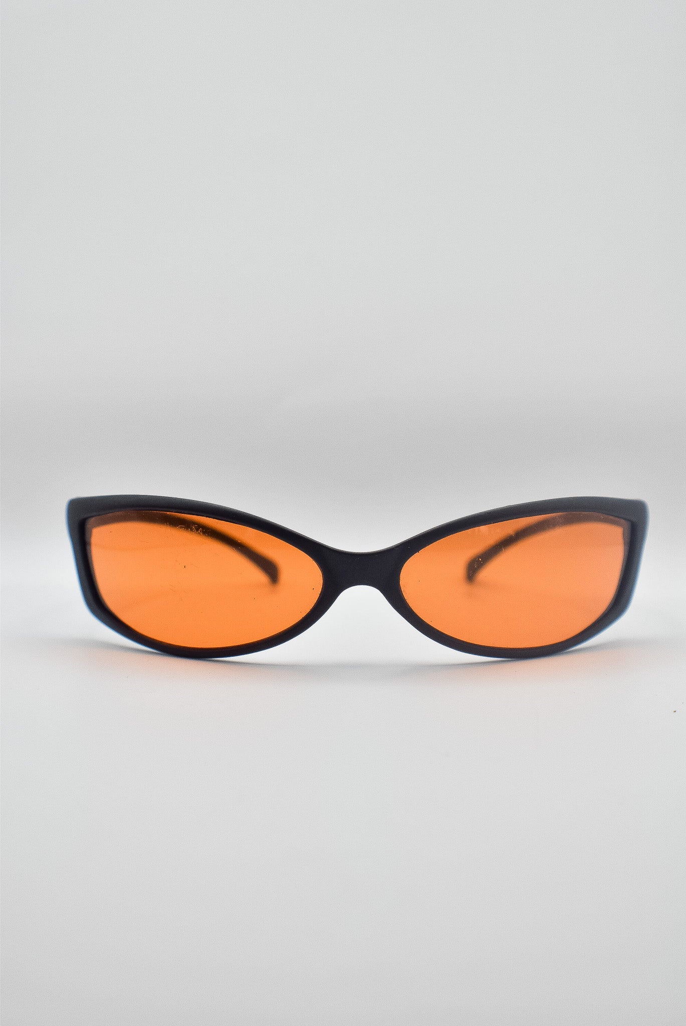Black-framed sunglasses with red tinted lenses on a light gray background