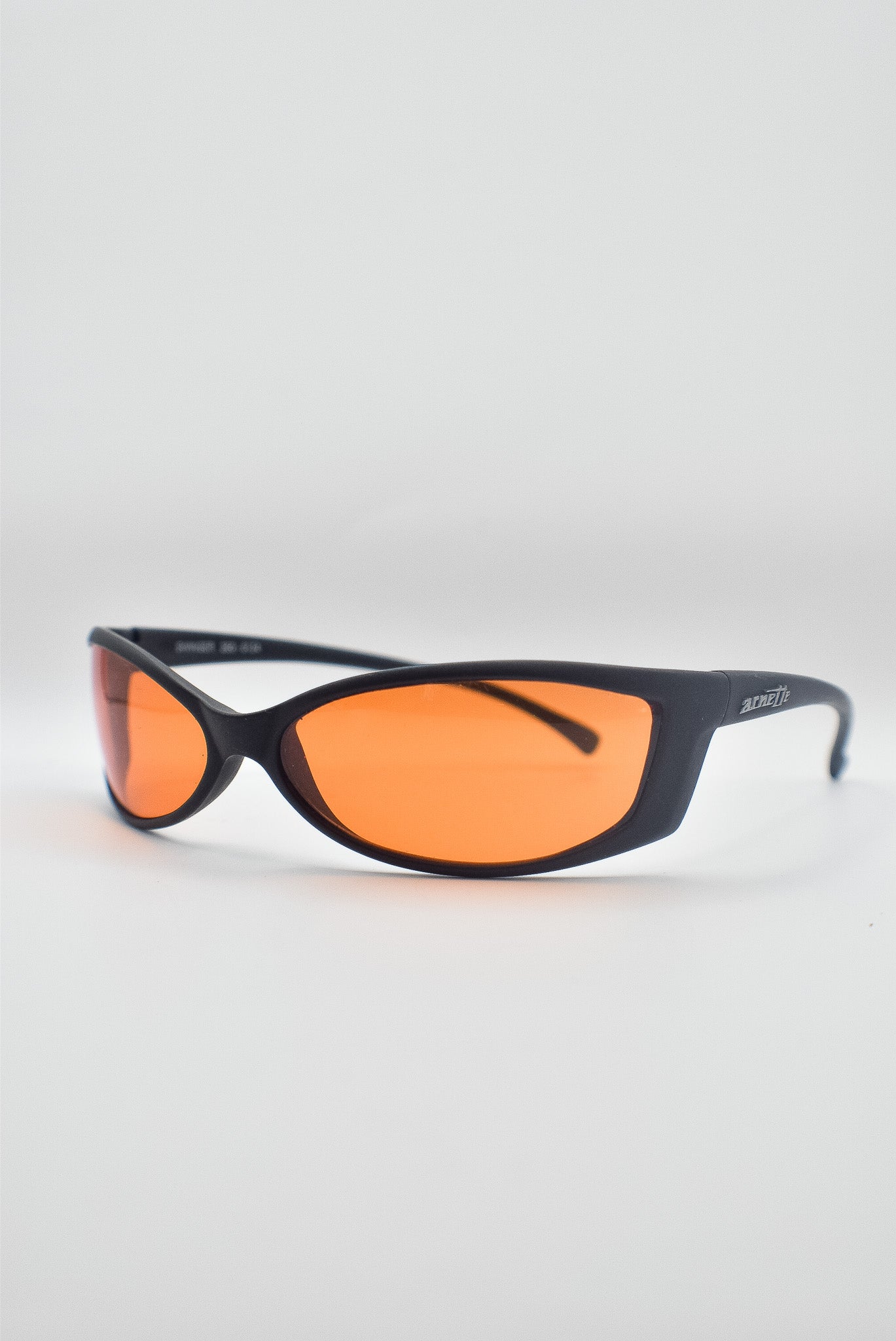 Black-framed sunglasses with red tinted lenses on a light gray background