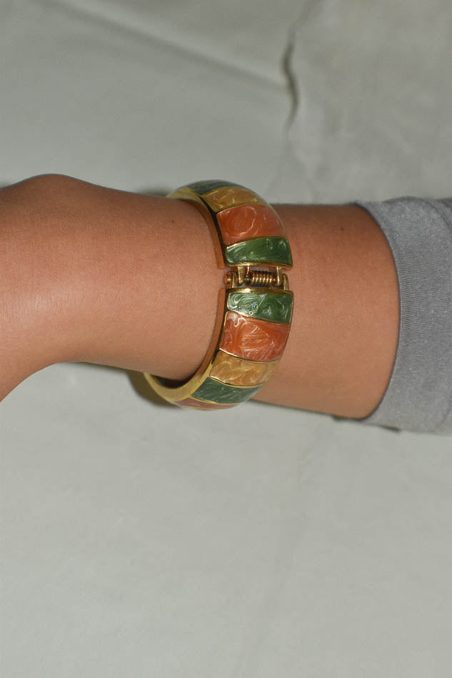 Colourful metal bracelet on a wrist against a neutral background