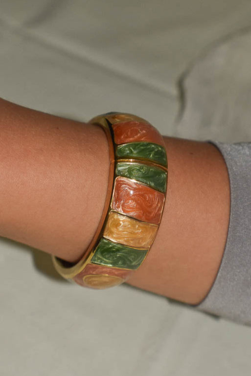 Colorful bangle on a wrist with a neutral background