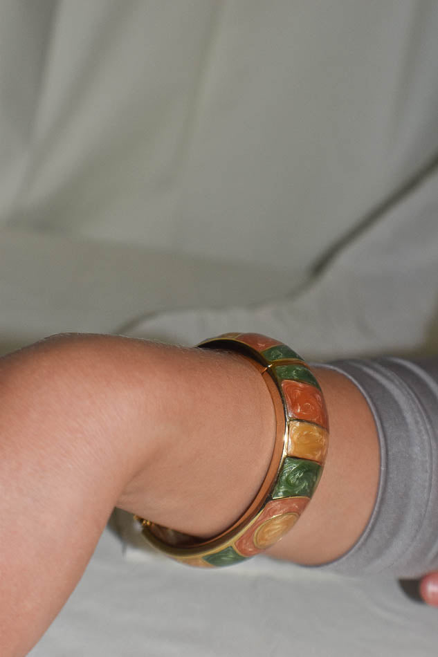 Close-up of a wrist wearing a colorful bangle on a neutral background