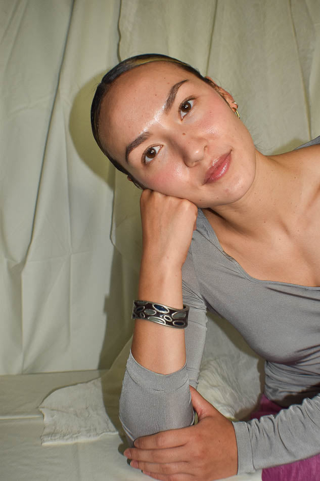 Woman wearing a gray long-sleeve top with a plain background