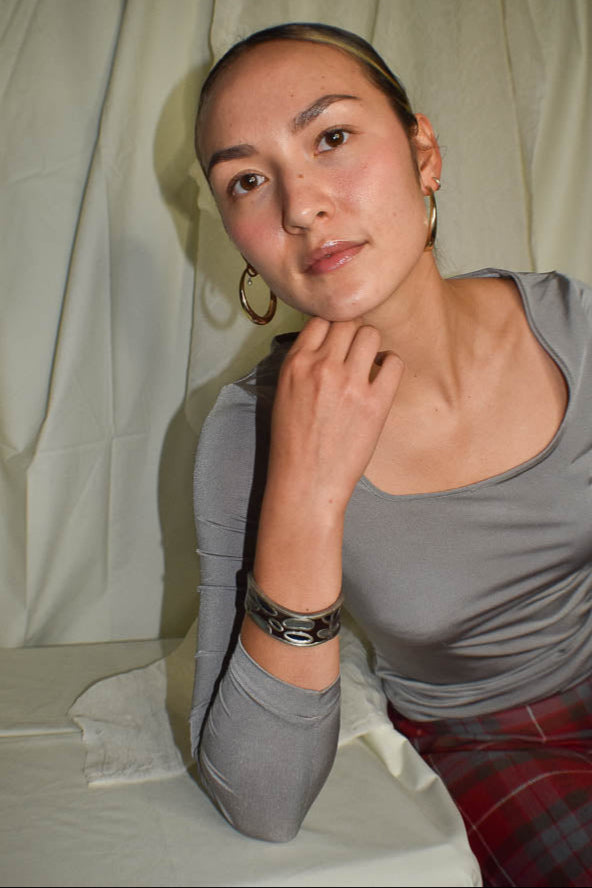 Woman wearing a gray shirt and plaid pants against a plain background