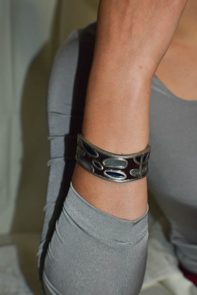 Person wearing a gray sleeveless top and bracelet on a neutral background