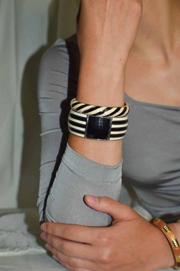 Person wearing a zebra-patterned belt with a large buckle, holding their waist.
