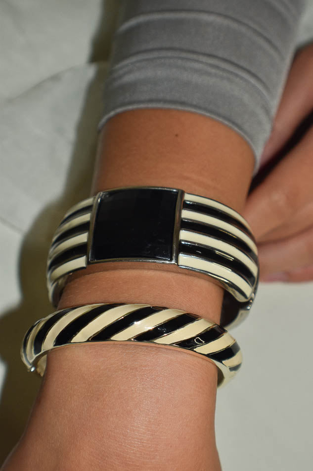 Black and white striped bangles on a wrist with a neutral background