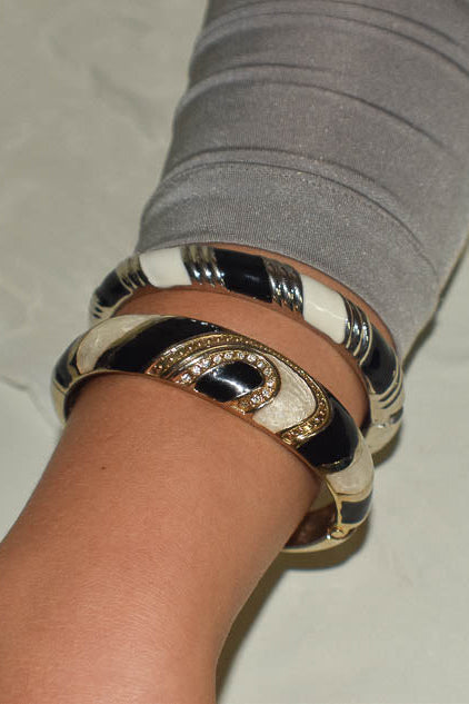 Close-up of a wrist wearing multiple metallic bracelets on a light background