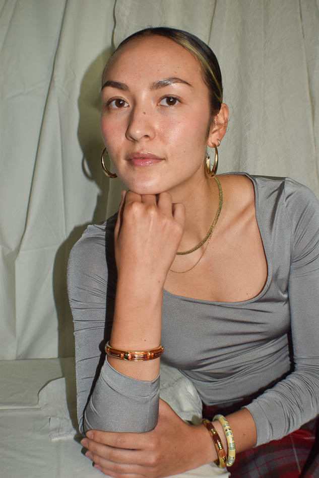 Woman wearing a gray top with jewelry against a plain background