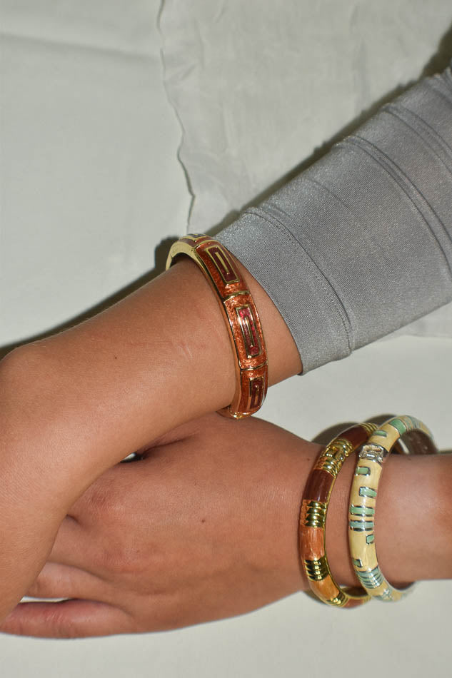 Close-up of a wrist wearing multiple bracelets on a neutral background