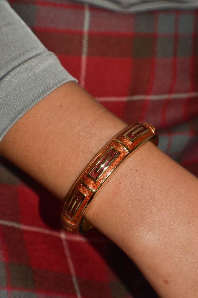 Gold bracelet on a wrist with a red plaid background