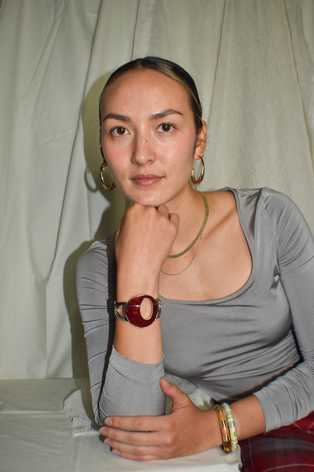 Woman wearing a gray long-sleeve top with a watch on her wrist against a plain background