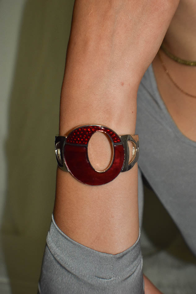 Close-up of a red and silver bracelet on a person's wrist.