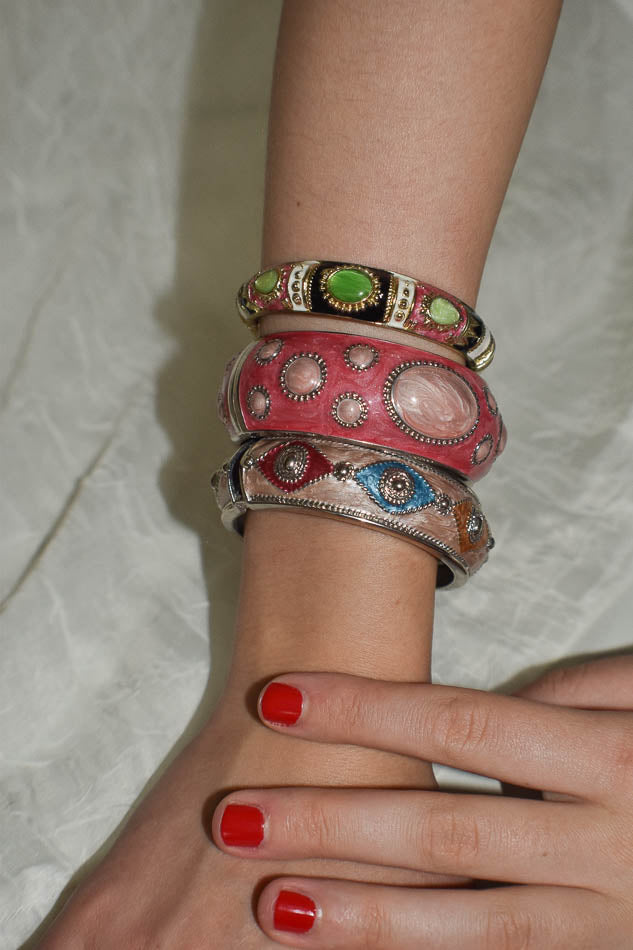 Close-up of a wrist wearing multiple colorful bracelets on a white fabric background