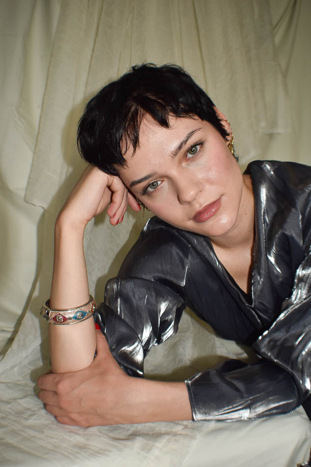 Person wearing a shiny silver jacket against a neutral background