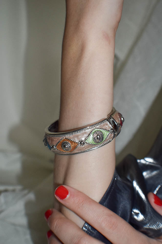 Close-up of a hand wearing an ornate bracelet with a neutral background