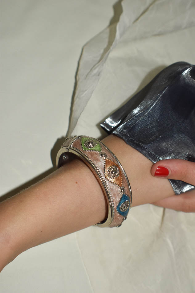 Hand wearing a colorful bracelet on a plain background