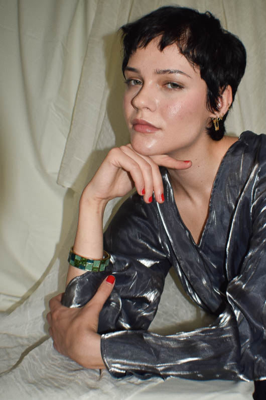 Woman wearing a shiny silver jacket against a neutral background