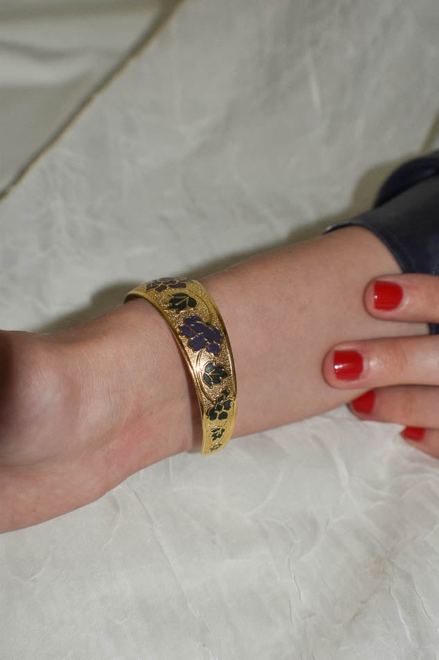 Gold bracelet with purple stones on a wrist against a white background