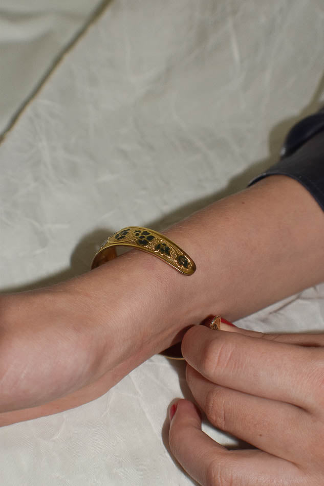 Gold bracelet on a wrist against a light background