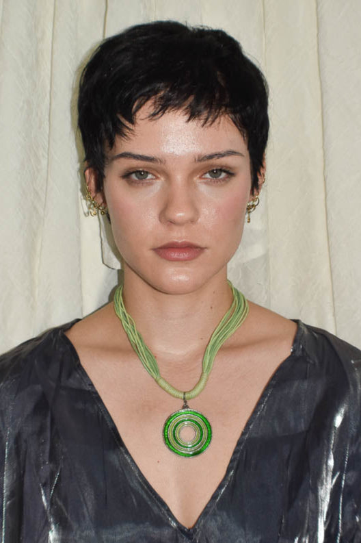 Woman wearing a green necklace against a neutral background