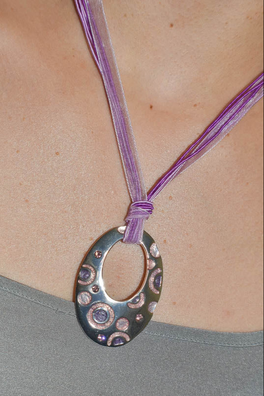 Necklace with a circular pendant on a person wearing a gray top.
