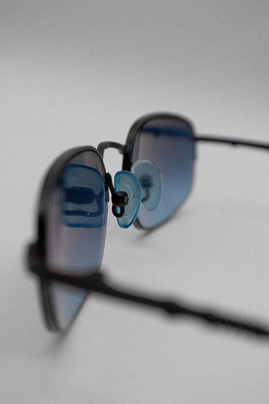 A pair of vintage blue tinted sunglasses with a black frame and arms, featuring a blue ombre tinted lens.