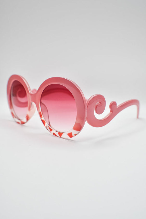 Pink sunglasses with a decorative frame on a light gray background
