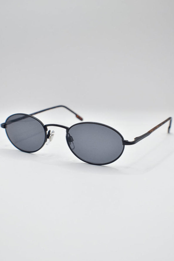 Round sunglasses with dark lenses on a light gray background