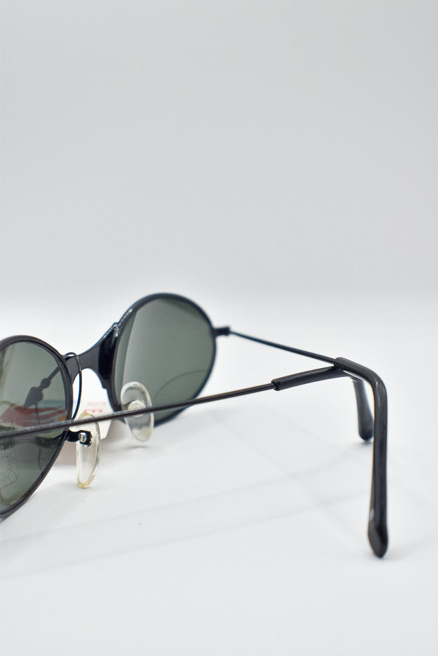Sunglasses with black frame and green lenses on a white background