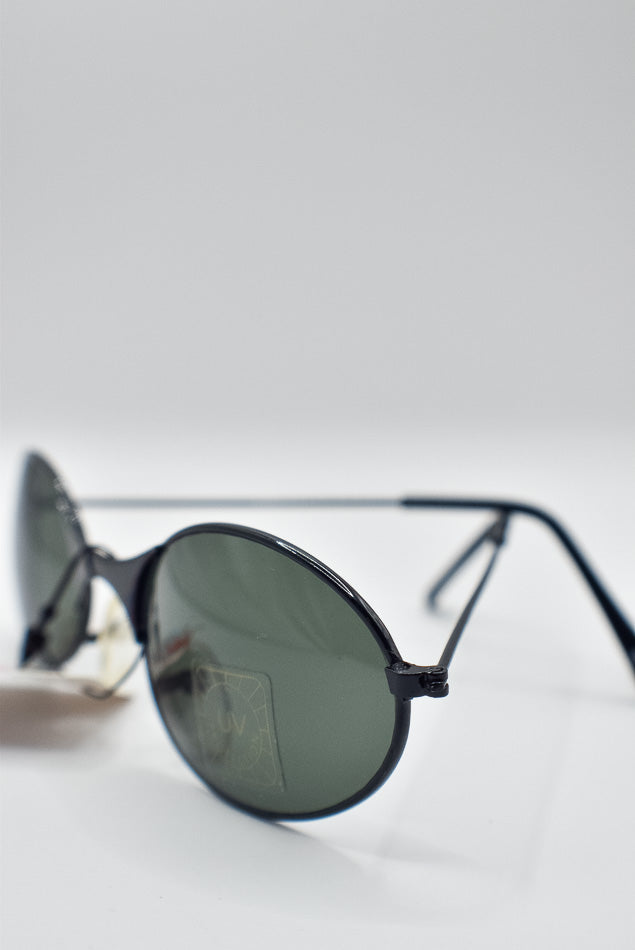 Round sunglasses with dark lenses on a light gray background