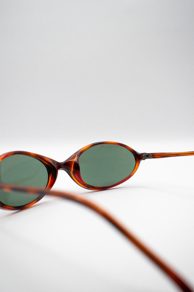 Sunglasses with tortoiseshell frame and dark lenses on a light gray background
