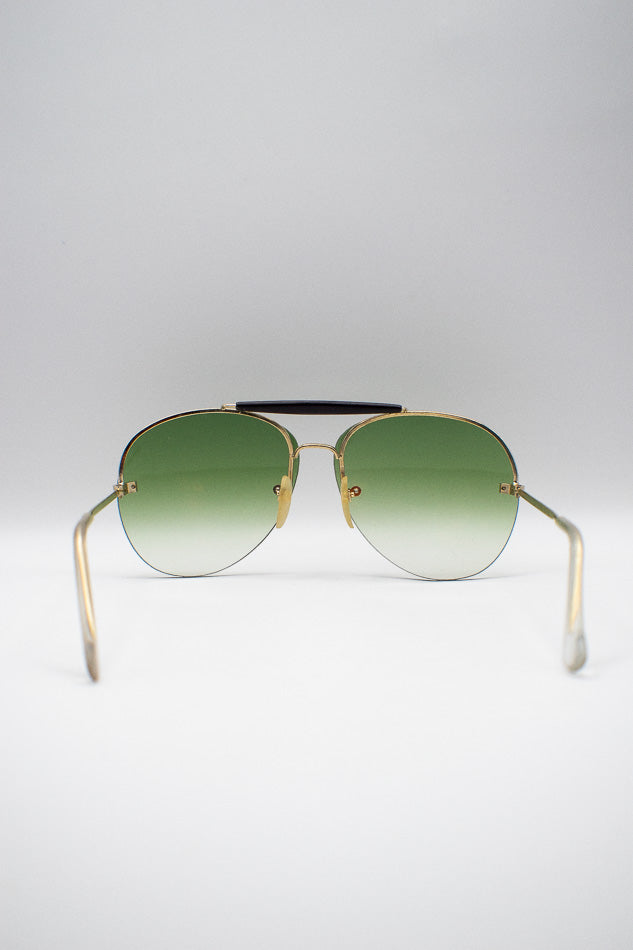 Aviator sunglasses with green gradient lenses on a light gray background