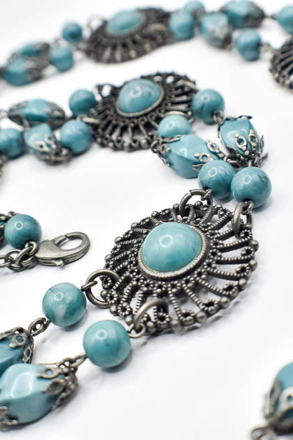 Necklace with blue beads and silver clasps on a white background