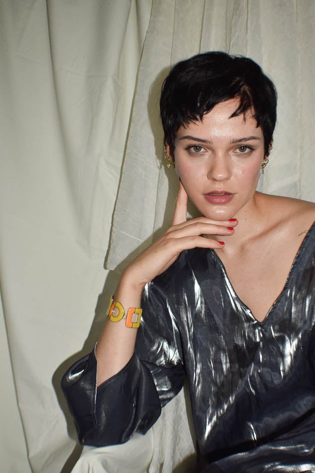 Woman wearing a metallic silver top against a plain background