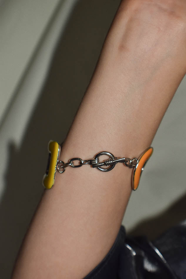 Bracelet with yellow and orange accents on a wrist against a neutral background