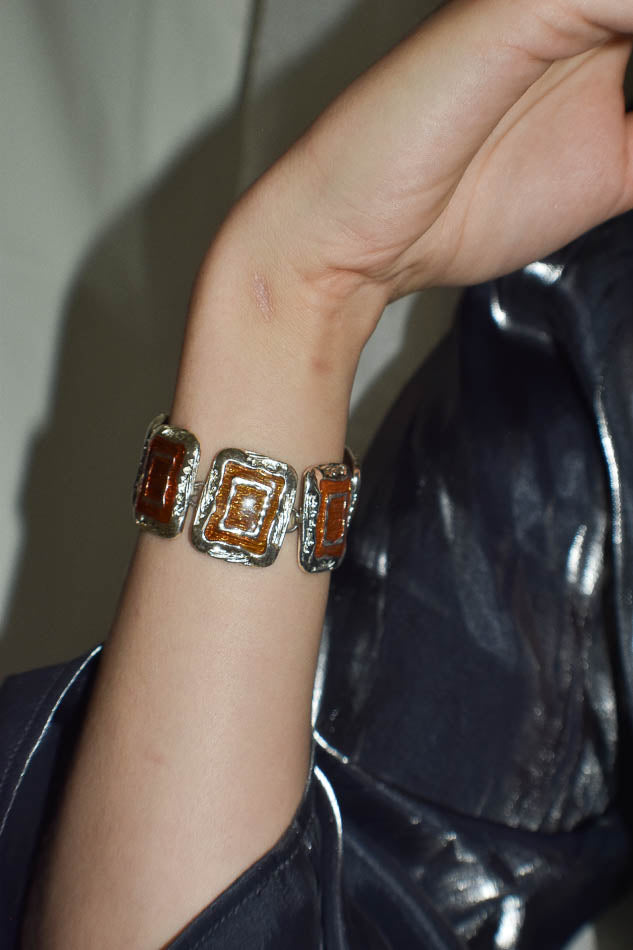 Bracelet with square design on a wrist against a dark background