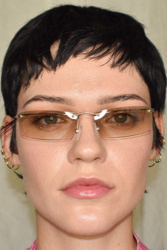 Close-up of a person with short black hair and glasses against a neutral background
